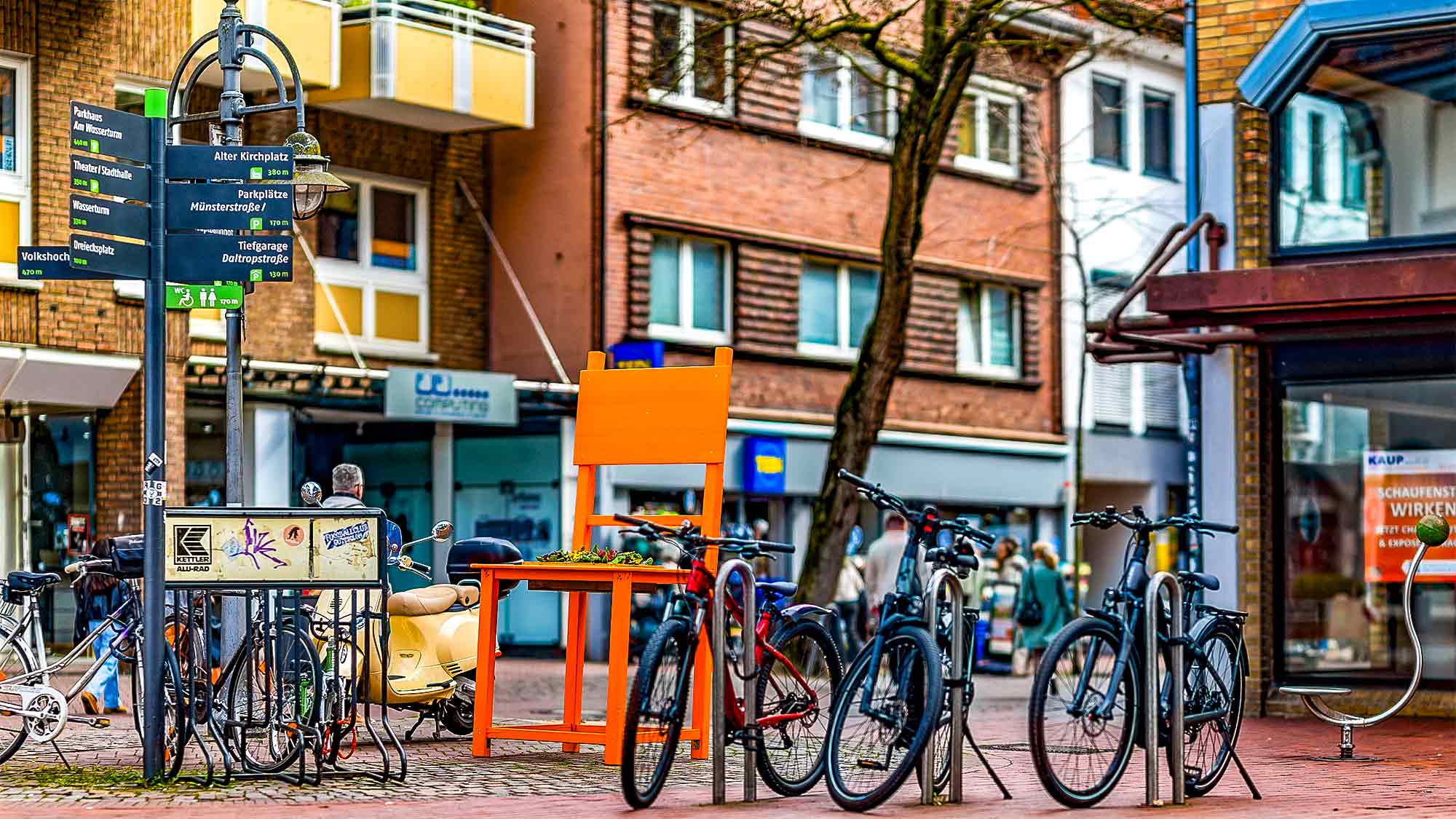 NOW Commons: »Gütersloher Frühling 2026«, Orange Chair mit Veilchen, Fußgängerzone Königstraße Gütersloh NOW Commons: »Gütersloher Frühling 2026«, Orange Chair mit Veilchen, Fußgängerzone Königstraße Gütersloh